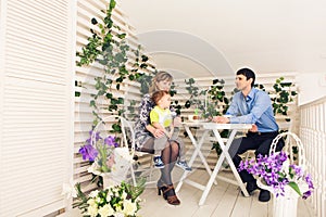 Family, parenthood, happy birthday and holiday concept - happy parents and child at a table drinking tea and eating cake