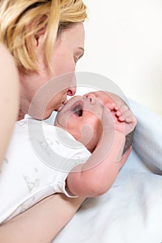 Family, parenting and child care concept - happy mother kissing adorable baby