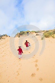 The family, parents and children are climbing the sand dune.