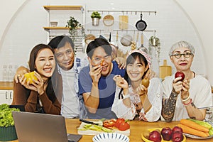 Family, parents, sons and daughters enjoy cooking in the kitchen, looking at the camera smiling happily.