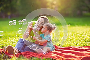 Family in park -Female child blows soup foam and make bubbles wi
