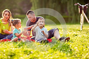 Family in park -Male child blow soup foam and make bubbles in na