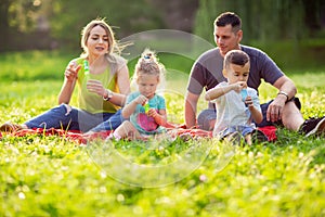 Family in park -Male and female child blow soap bubbles outdoor