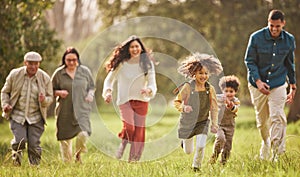 Family, park and parents running with children in nature for playing, bonding and fun together in field. Happy