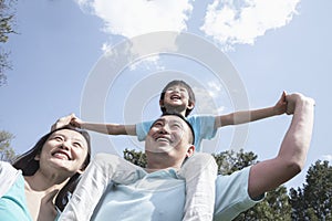 Family in park with son on father's shoulders.