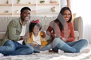 Family Pastime. Cheerful Black Parents Playing Video Games With Daughter At Home