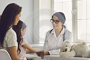 Family patients are consulted by a general practitioner in a medical clinic. Woman doctor smiling at the girl and her