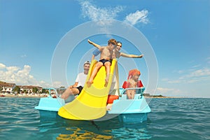 Family on pedal boat with yellow slide in sea