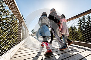Family people walking wooden treetop bridge canopy walkway in winter
