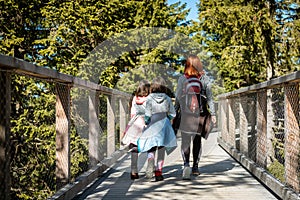 Family people walking wooden treetop bridge canopy walkway in winter