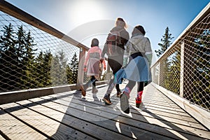 Family people walking wooden treetop bridge canopy walkway in winter