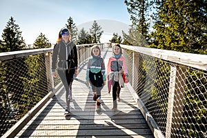 Family people walking wooden treetop bridge canopy walkway in winter