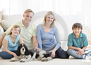 Family With Pet Dog Sitting On Floor In Living Room