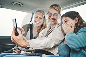 Family, phone and women taking a selfie in the car on road trip adventure. Grandmother, mom and girl smile for picture