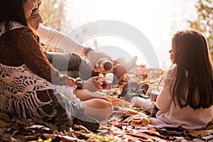 Family picnic in the autumn park. Family drinking tea