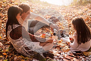 Family picnic in the autumn park. Family drinking tea