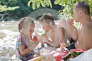Family picnic of father and two children with juicy watermelon