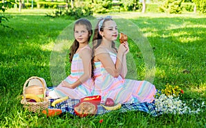 Family picnic. Little girls eat picnic meal on green grass. Summer vacation. Eating outdoors. Enjoy the day with tasty