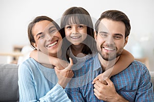 Family picture of funny preschooler hug smiling parents