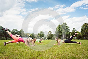 Family planking outdoors in meadow with fitness teacher photo