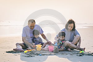 Happy healthy family Grandfather ,Grandmother and Nephew building sand castle on the beach smiling and carefree. photo