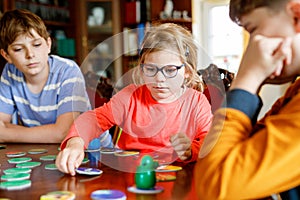 Family playing board game at home. Kids play strategic game. Little sister girl and two school brothers boys. Fun indoor