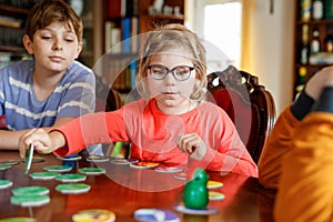 Family playing board game at home. Kids play strategic game. Little sister girl and two school brothers boys. Fun indoor