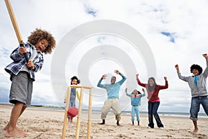 Family playing cricket on beach