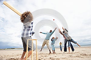 Family playing cricket on beach