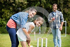 Family playing cricket in park