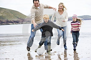 Family playing football on beach