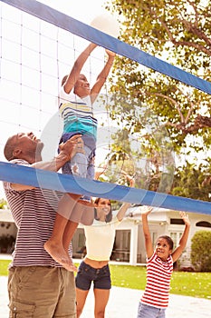 Family Playing Game Of Volleyball In Garden