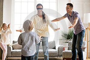 Family playing hide and seek game together with blindfolded moth