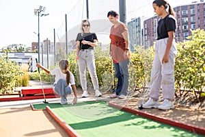 family playing mini golf on a cruise liner. Child having fun with active leisure on vacations.