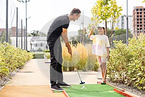 Family playing miniature golf outdoors