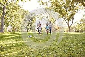 Family Playing Soccer In Park Together