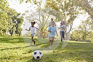 Family Playing Soccer In Park Together