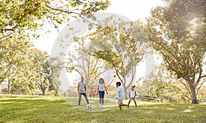 Family Playing Soccer In Park Together