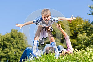 Family playing with son lying in grass on meadow