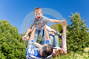 Family playing with son lying in grass on meadow