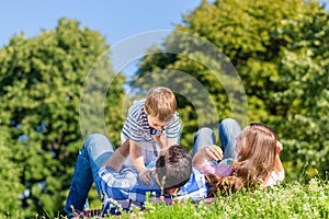 Family playing with son lying in grass on meadow