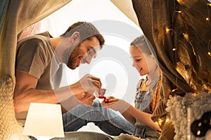 Family playing tea party in kids tent at home