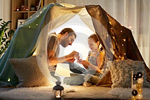 Family playing tea party in kids tent at home