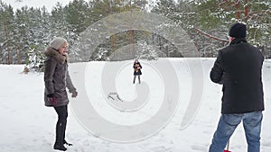 Family playing by throwing snowballs in the winter