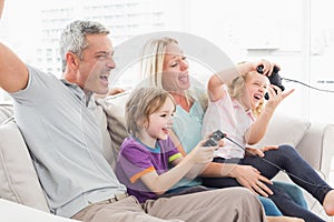 Family playing video game while sitting on sofa