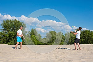 The family plays beach badminton. Father and son play badminton on the beach