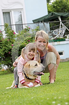 family plays with a dog a lawn at the house