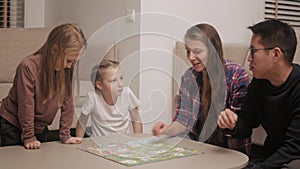 Family plays table game in the living room in the evening.