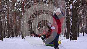 Family plays in the winter park during the Christmas holidays. Happy children and father winter sledding in the snow and