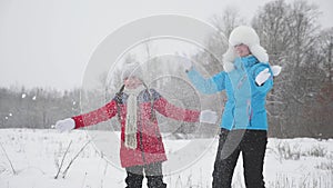 Family plays in the winter park for christmas vacation. happy mother and daughter throw snow up, Snow falls and sparkles